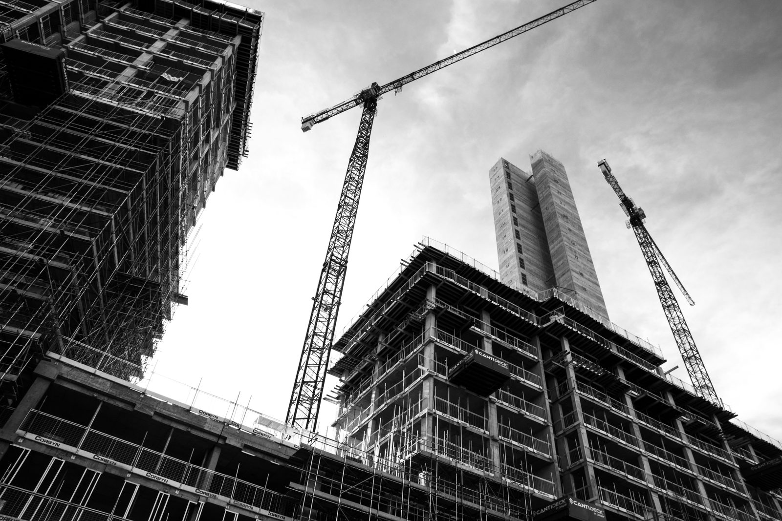 High-rise buildings under construction with tower cranes against an overcast sky